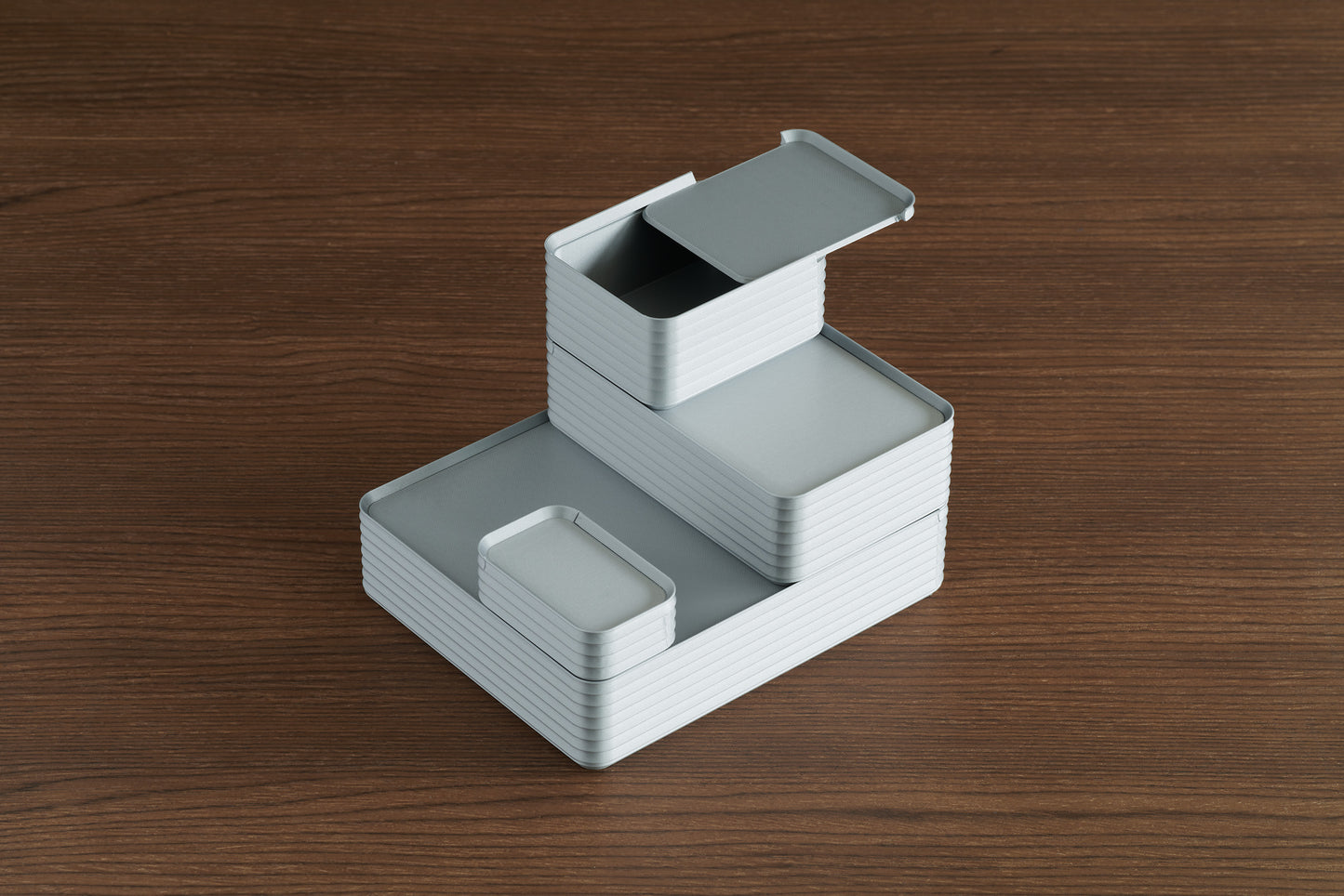 Arrangement of four stacked silver Z Co ribbed boxes in different sizes on a walnut surface, with the small box shown open to display its sliding lid design.