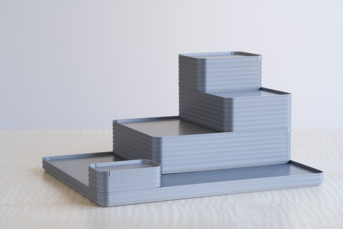Full silver-tone arrangement of Z Co Rib Series boxes, including a large tray, double-wide box, original box, small box, and mini box. The metallic silver finish highlights the ribbed texture, forming a sophisticated and functional stacked display on the maple table.