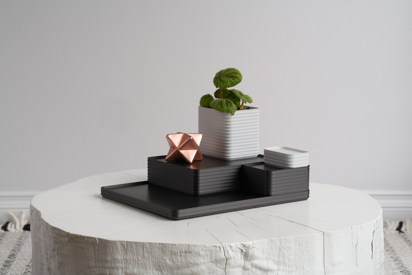 A stacked set of metallic iron gray Rib Series boxes, tray, and planter styled with a cactus on a white stool — showing the endless arrangement potential of the Z Co Gift Card.