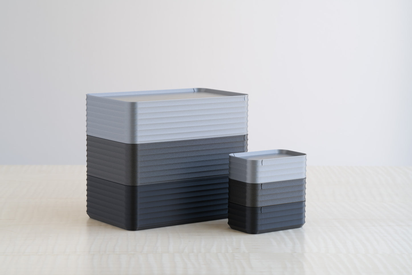 Side-by-side comparison arrangement of Z Co Rib Series Boxes in Silver, Metallic Iron Black, and Black, displayed neatly on a maple wood table.