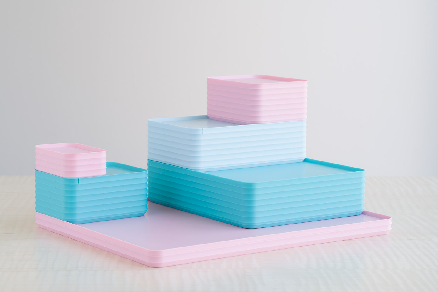 Playful pastel arrangement of Z Co Rib Series boxes in turquoise, matte light pink, and matte ice blue, stacked in a layered design on a maple table for a bright and cheerful aesthetic.