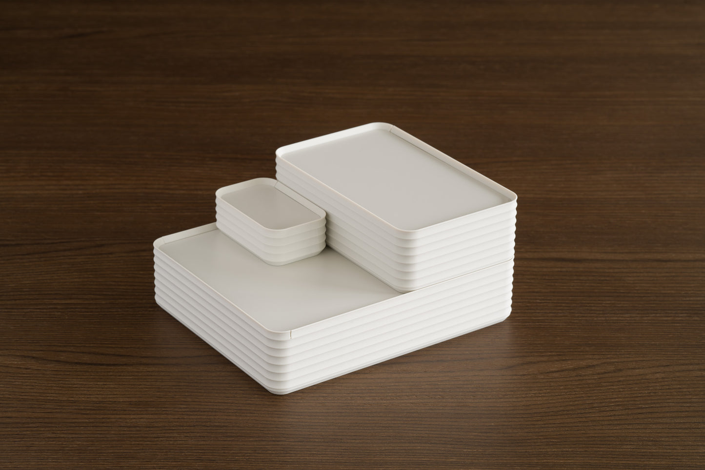 Arrangement of three Z Co Rib Series Boxes in bone white, stacked on a walnut surface. Includes the double-wide, original, and mini sizes, creating a stepped display with a clean, neutral aesthetic.
