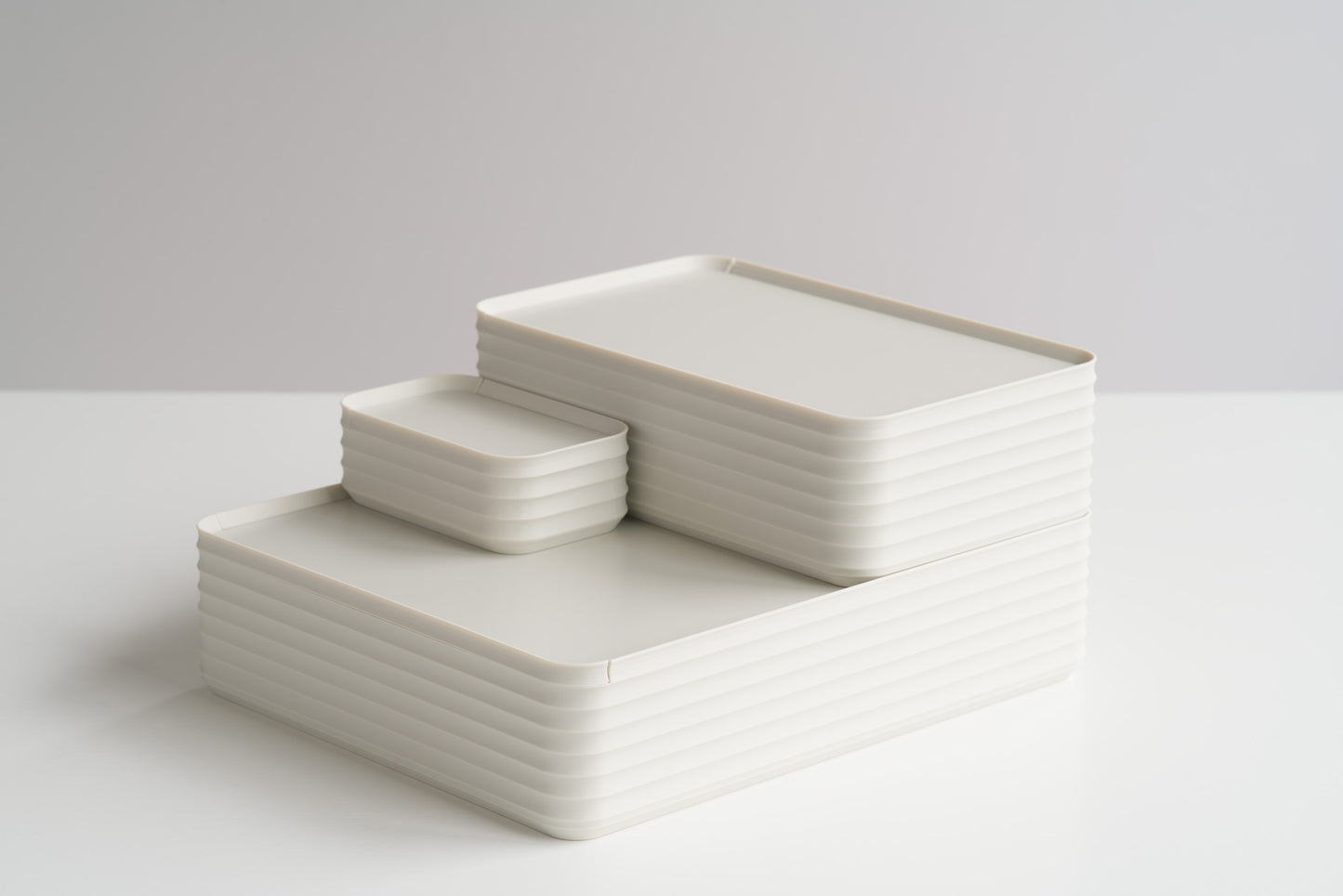 Three Z Co Rib Series Boxes in bone white stacked on a white tabletop, showcasing original, small, and mini sizes. Minimalist ribbed storage design in soft neutral tones.