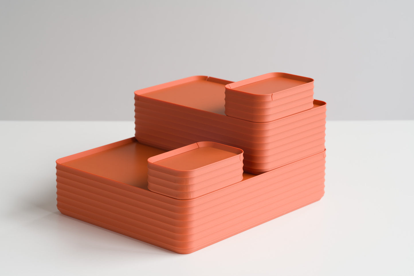 Four Z Co Rib Series Boxes in terracotta stacked on a white tabletop. Warm earthy tone highlights the ribbed storage design in mini, small, original, and double-wide sizes.