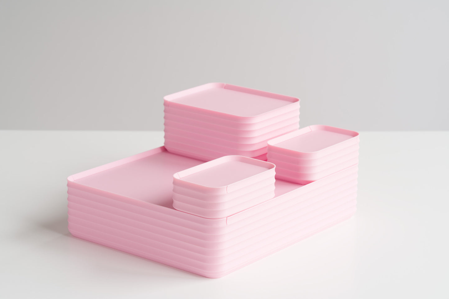 Set of four Z Co Rib Series Boxes in matte light pink, stacked on a white table. Their soft pastel pink color makes them perfect as baby girl keepsake boxes, ideal for storing cherished mementos or gifts. Includes mini, small, original, and double-wide sizes with ribbed modern design.