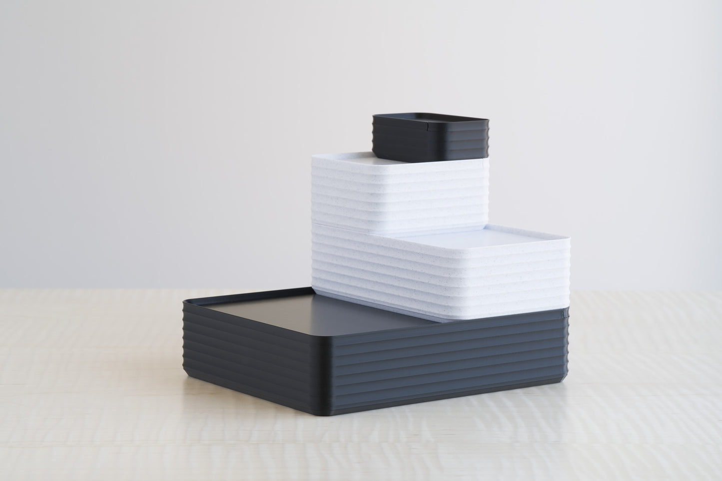 Arrangement of Z Co Rib Series boxes in marble white and black, stacked in a tiered display on a maple table. A modern color contrast that highlights the sleek ribbed design, ideal for decorative storage or gifting.