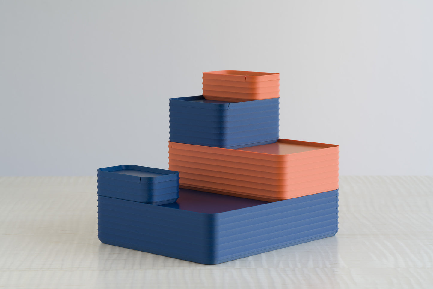 Z Co Rib Series boxes in matte blue and matte terracotta, arranged in a stepped configuration on a maple table. The earthy orange tones balance with the bold blue, creating a versatile storage and décor set.
