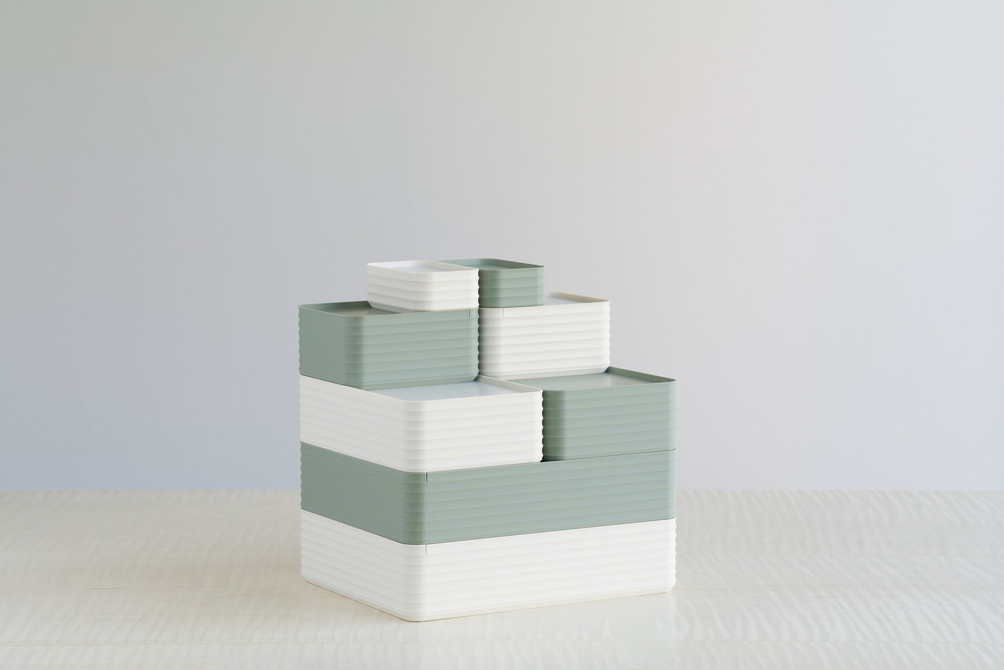 Stacked arrangement of Z Co Rib Series boxes in matte tranquil green and matte bone white on a maple table. A soft, minimal palette that blends natural and modern aesthetics for home or office organization.