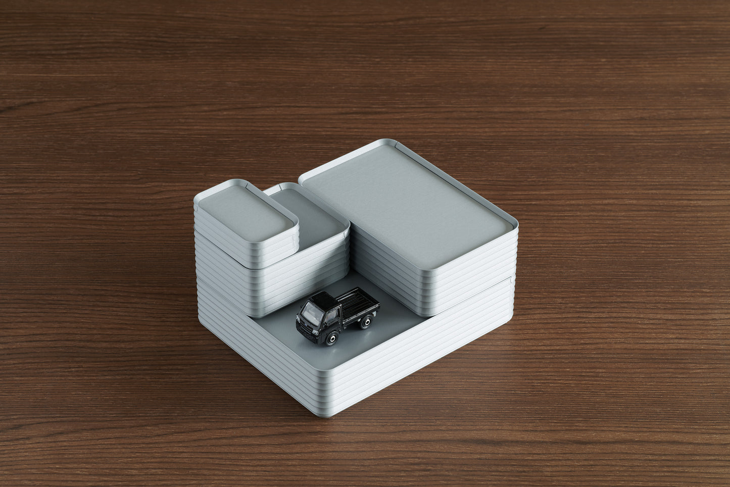 Stacked arrangement of four silver Z Co Rib Series Boxes in various sizes, including a double-wide, original, small, and mini, with a small black toy truck on a walnut surface.