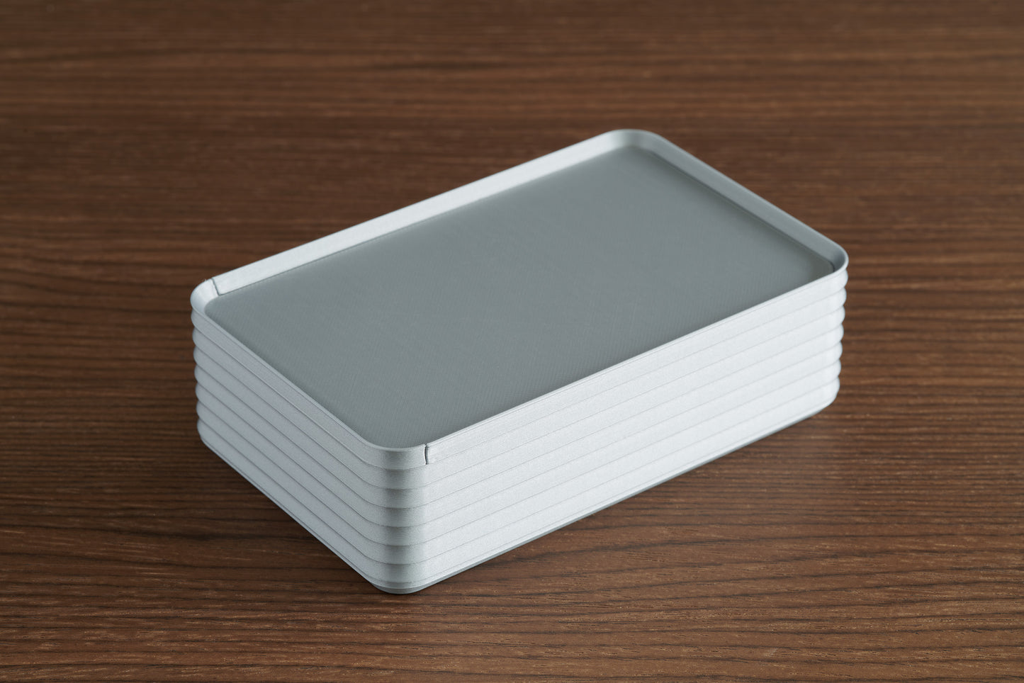 Silver Original Rib Series Box tarot card deck storage resting closed on a walnut surface, highlighting the textured ribbed design and smooth sliding lid.