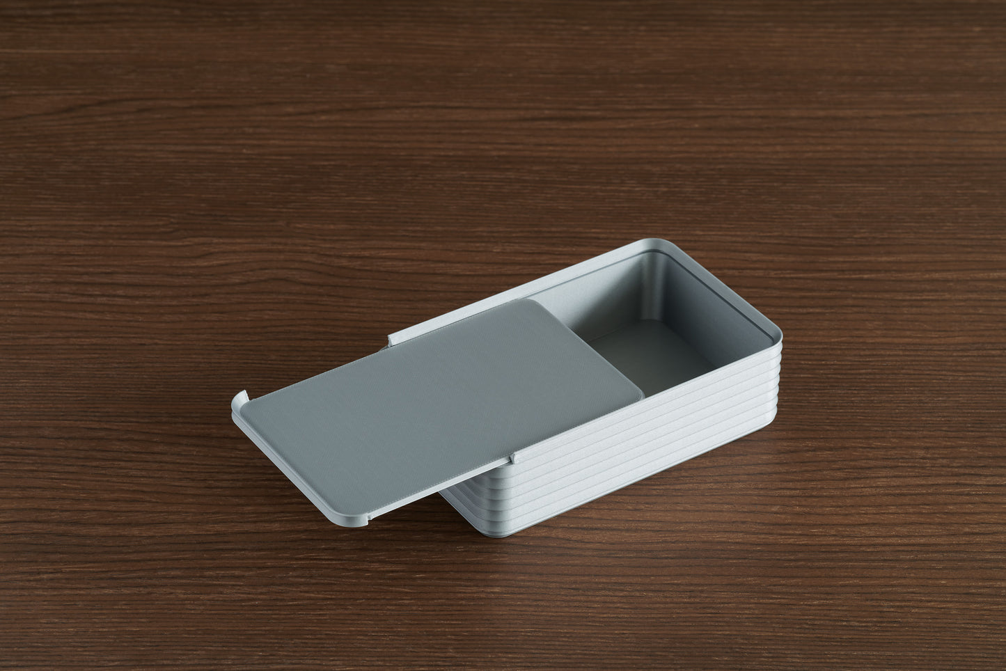 Silver Original Rib Series Box on walnut surface with lid partially open, showing the ribbed detail and interior compartment.