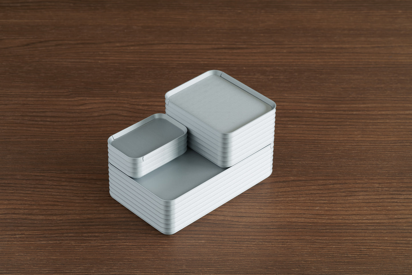 Arrangement of Z Co Rib Series boxes in silver finish, featuring mini and original sizes stacked together on a walnut wood surface.