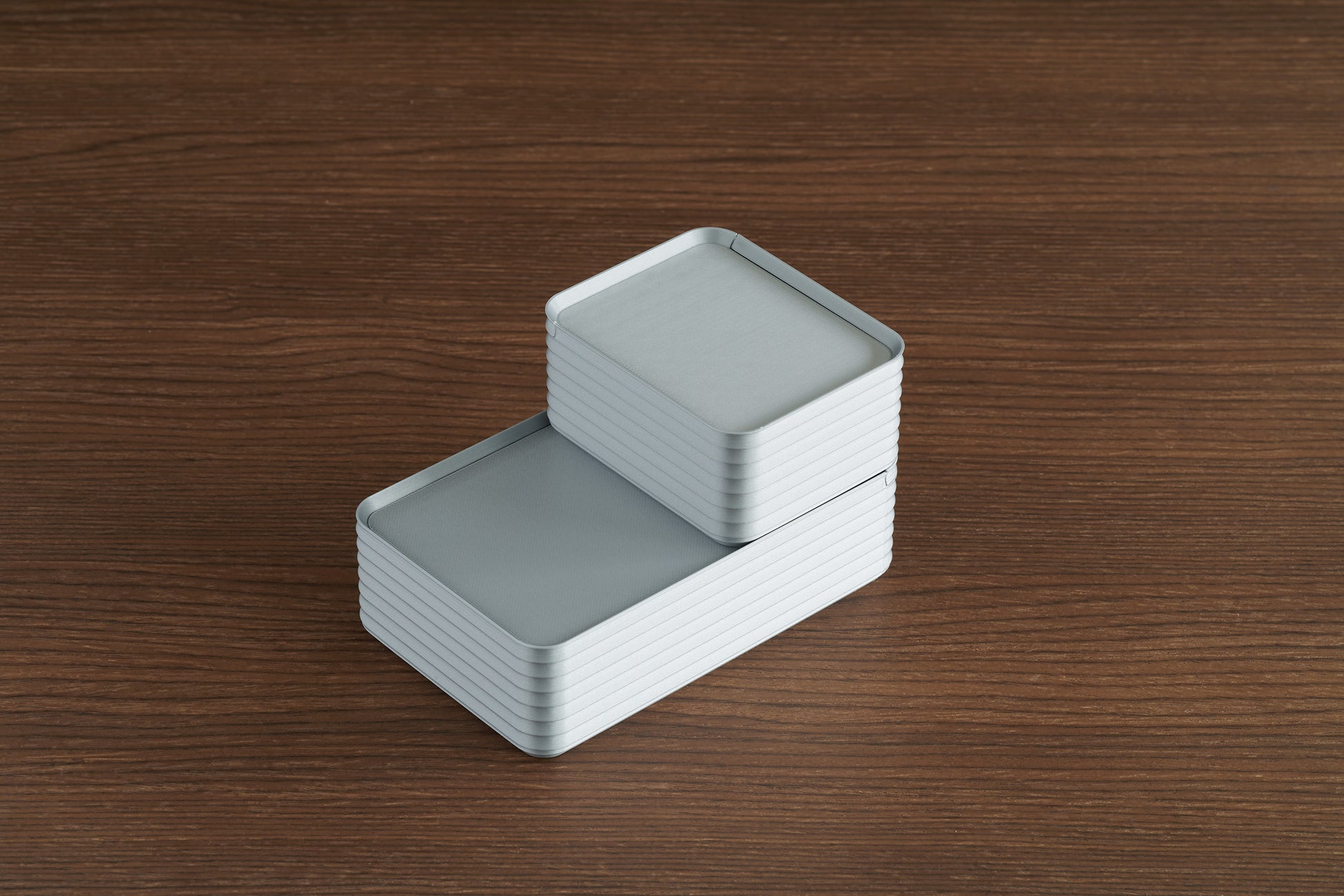 Arrangement of silver Z Co ribbed boxes on a walnut surface, showing the small box stacked on top of the original box, both with closed lids.