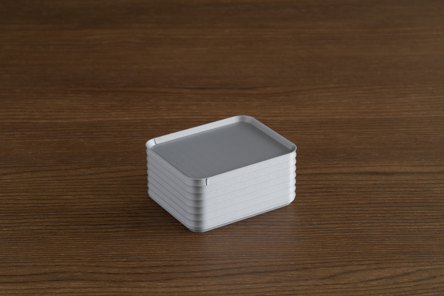 Small silver Z Co box with lid closed, resting on a walnut wood surface.