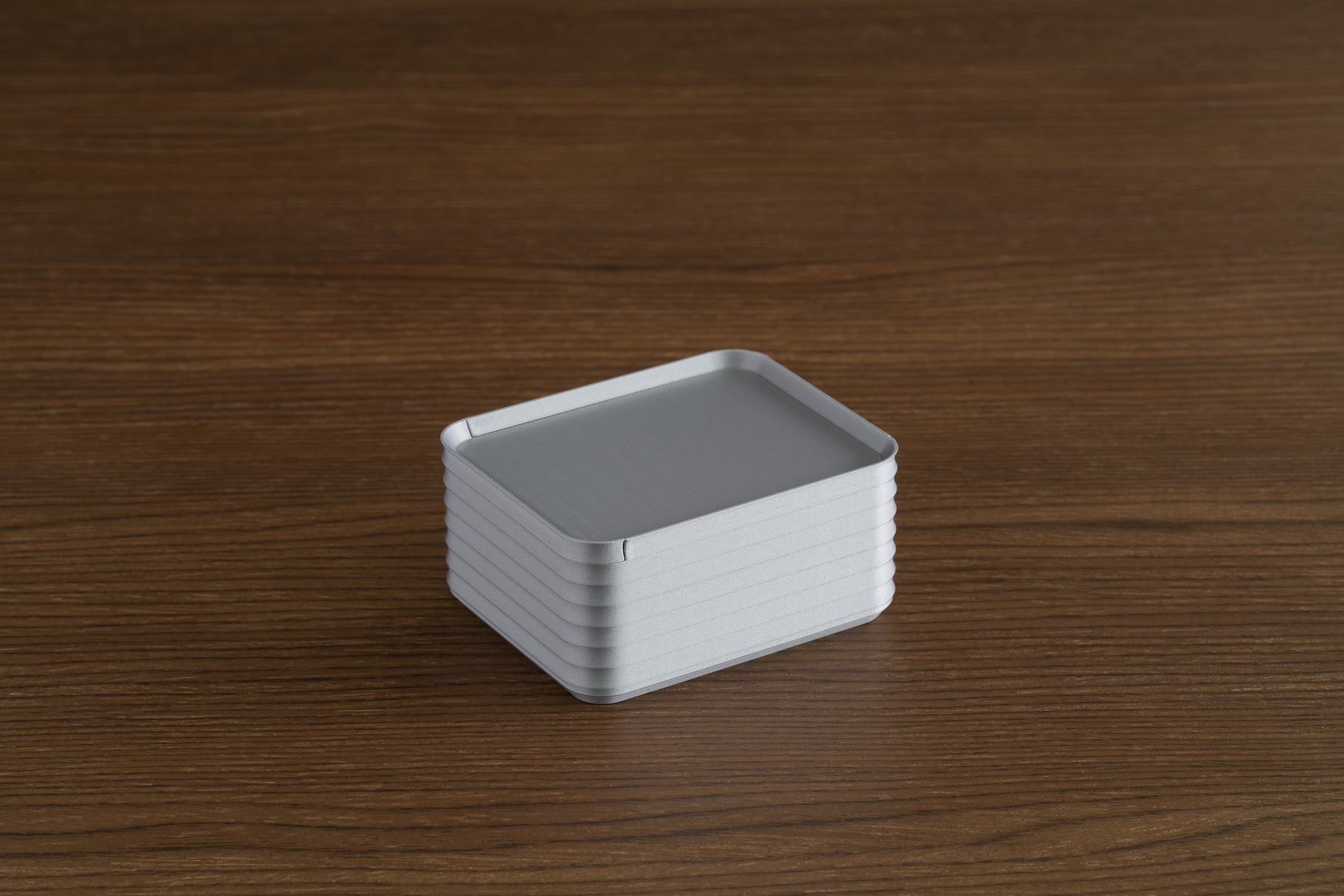 Small silver Z Co box with lid closed, resting on a walnut wood surface.