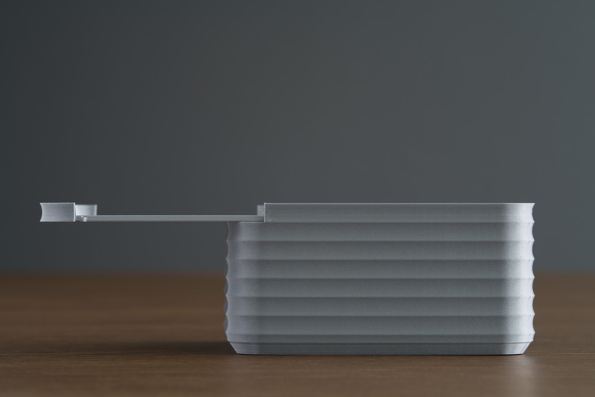 Small Silver Z Co ribbed box on walnut surface, horizontal side view with lid fully extended open.
