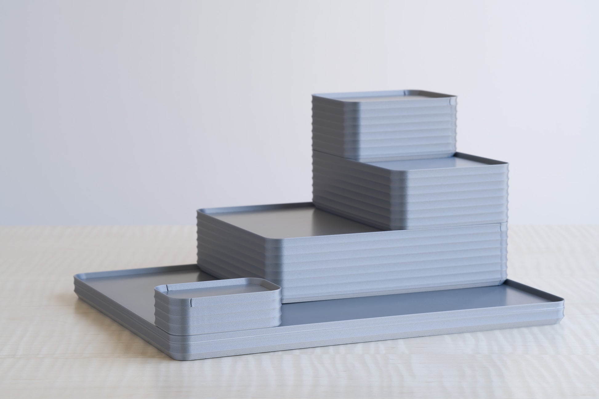 Full silver-tone arrangement of Z Co Rib Series boxes, including a large tray, double-wide box, original box, small box, and mini box. The metallic silver finish highlights the ribbed texture, forming a sophisticated and functional stacked display on the maple table.