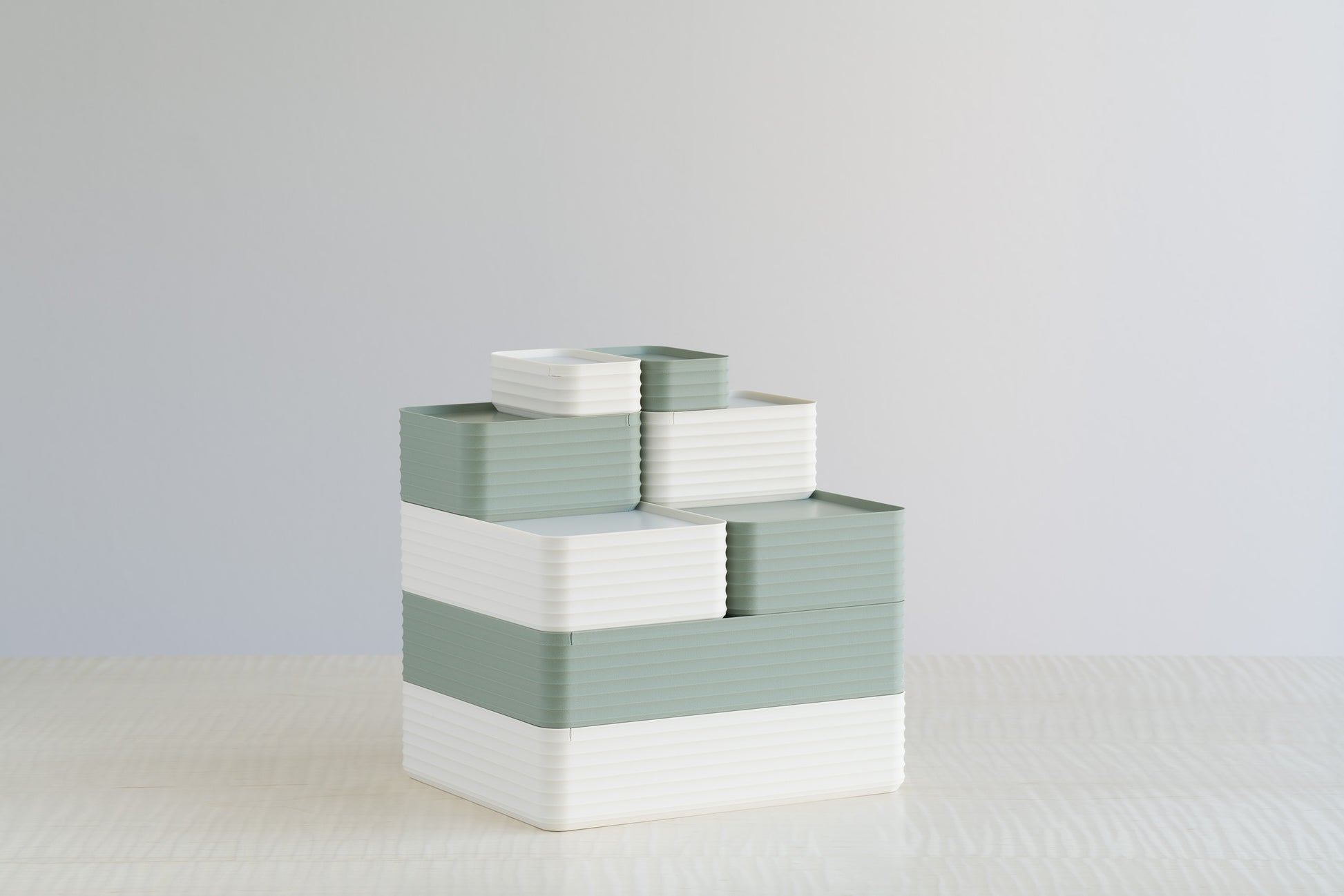 Stacked arrangement of Z Co Rib Series boxes in matte tranquil green and matte bone white on a maple table. A soft, minimal palette that blends natural and modern aesthetics for home or office organization.