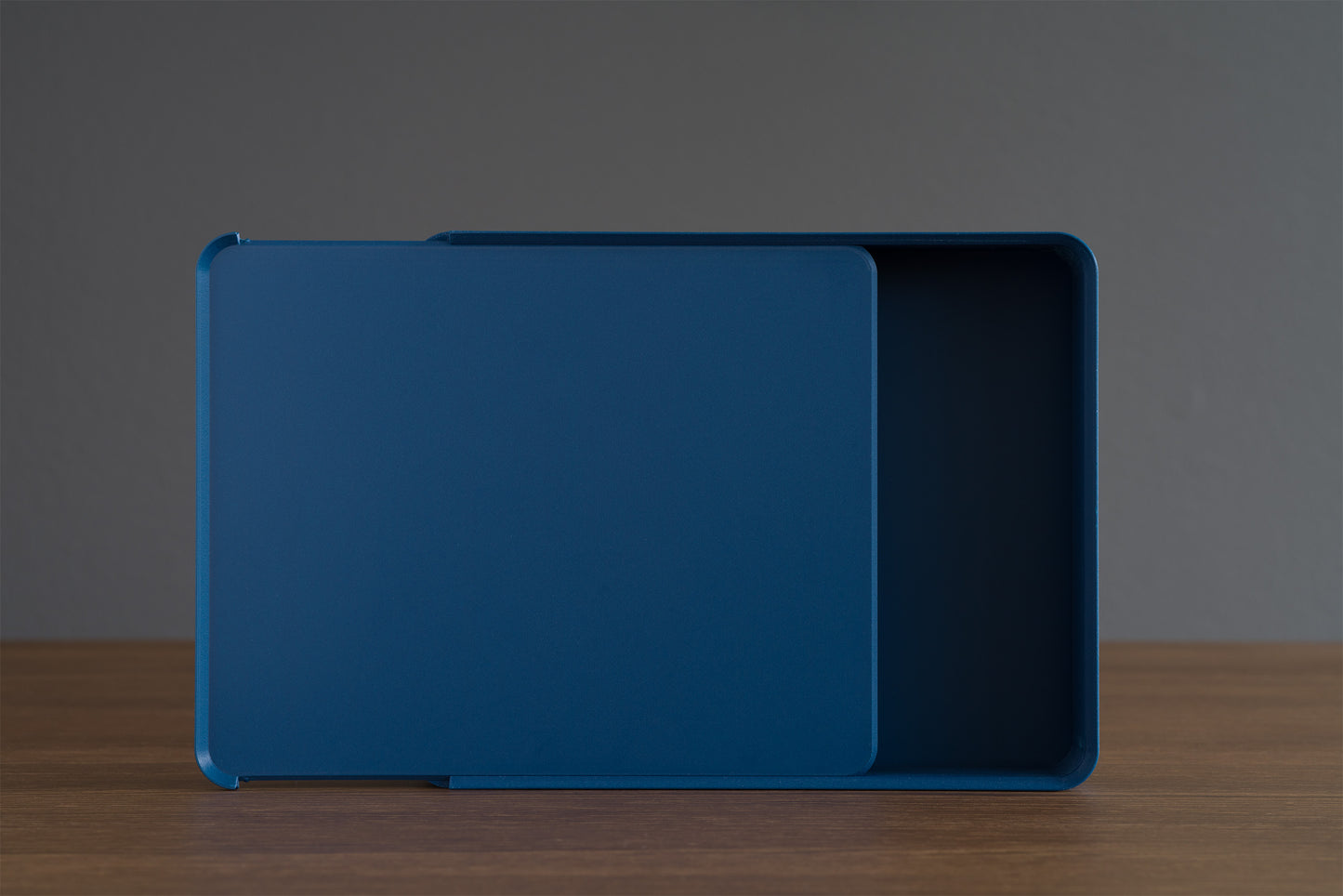 Top view of the Z Co Rib Series Double-Wide Box in matte dark blue, upright on its side with the sliding lid halfway open. Contemporary ribbed storage box photographed on walnut wood.