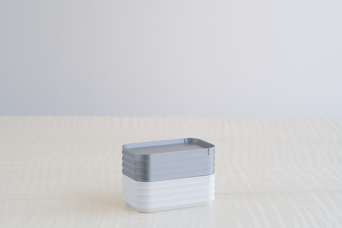 Two stacked Z Co Rib Series mini boxes in silver and light gray, creating a sleek, minimal contrast of metallic and soft neutral finishes.