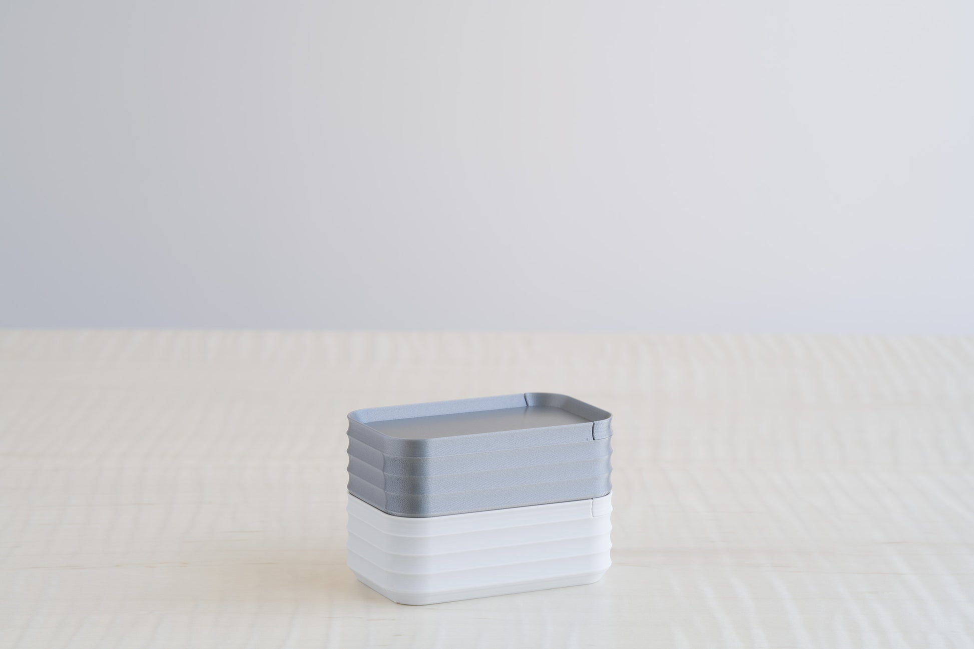 Two stacked Z Co Rib Series mini boxes in silver and light gray, creating a sleek, minimal contrast of metallic and soft neutral finishes.