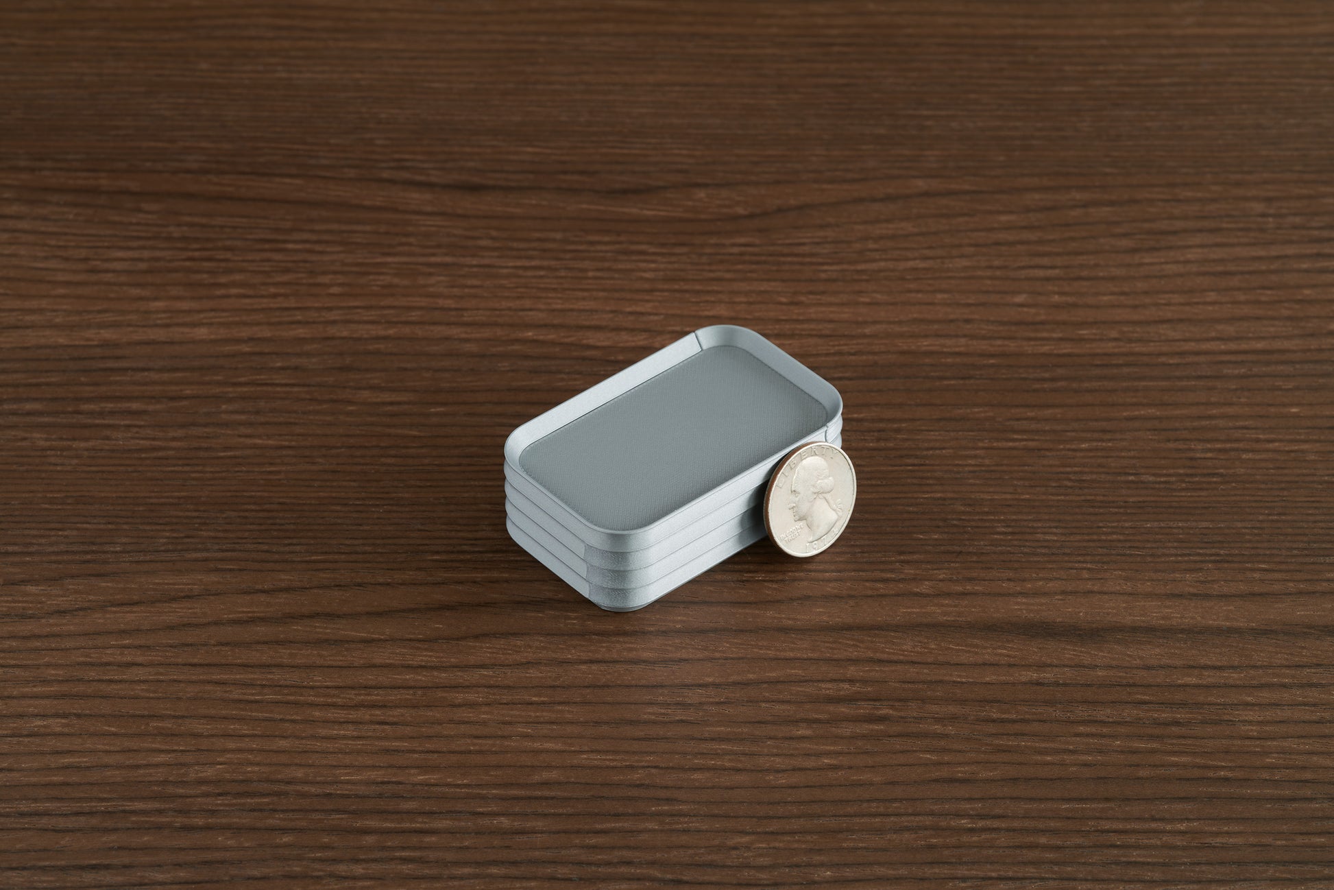 Silver Z Co mini box on walnut surface with quarter leaning against side for scale