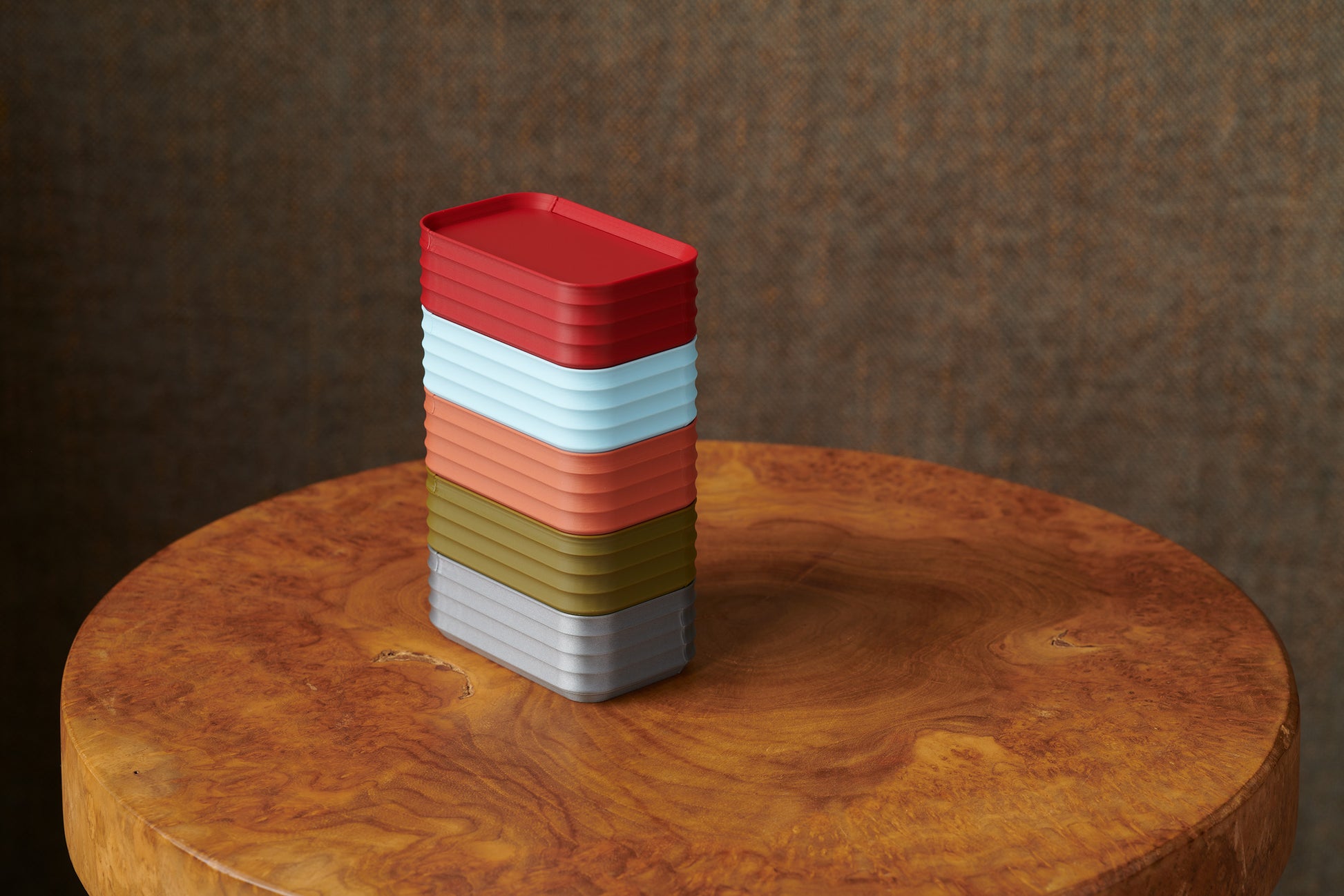 Stack of Z Co mini boxes in red, ice blue, terracotta, army green, and silver on wood stool