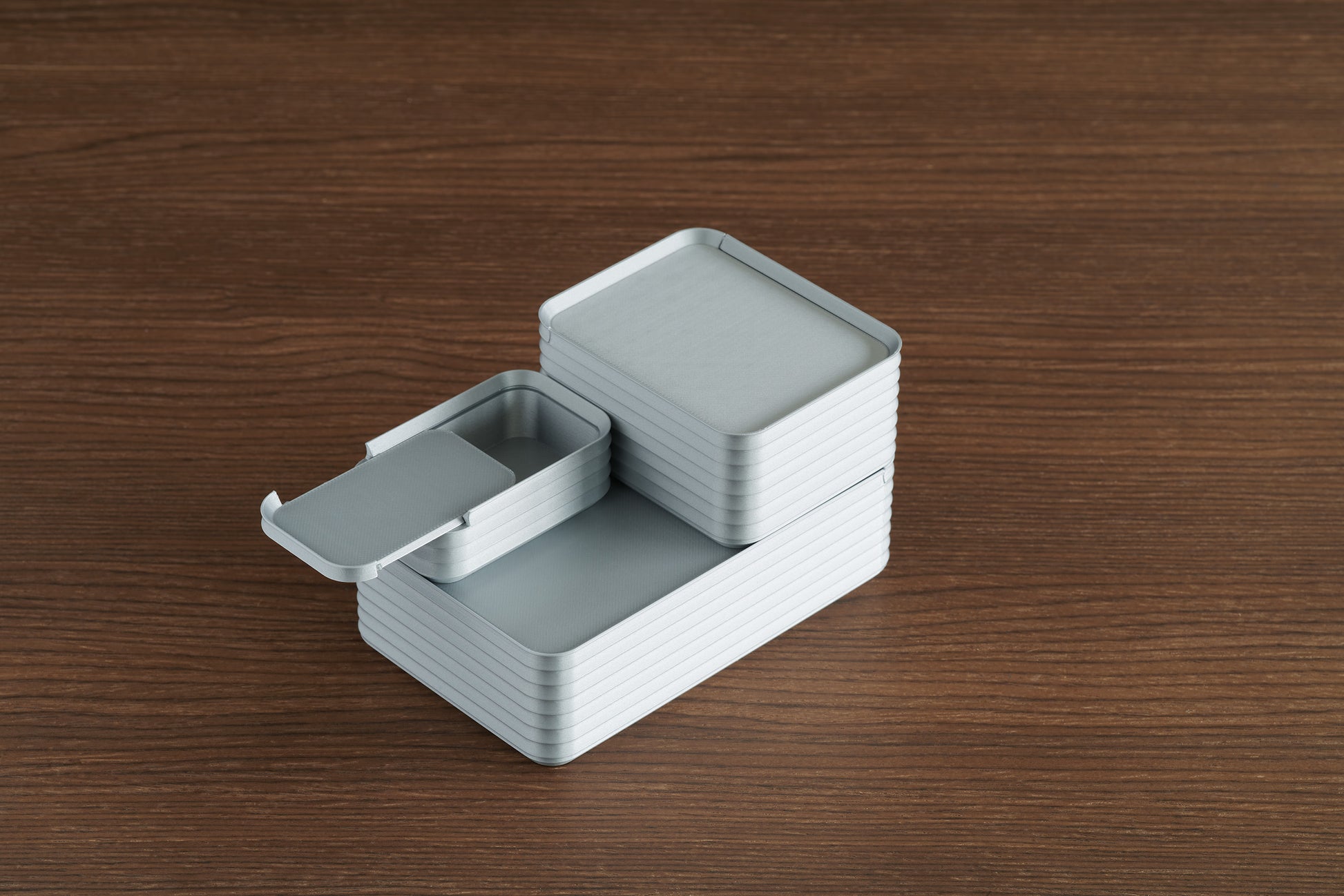 Arrangement of three silver Z Co boxes on walnut surface with mini box lid open