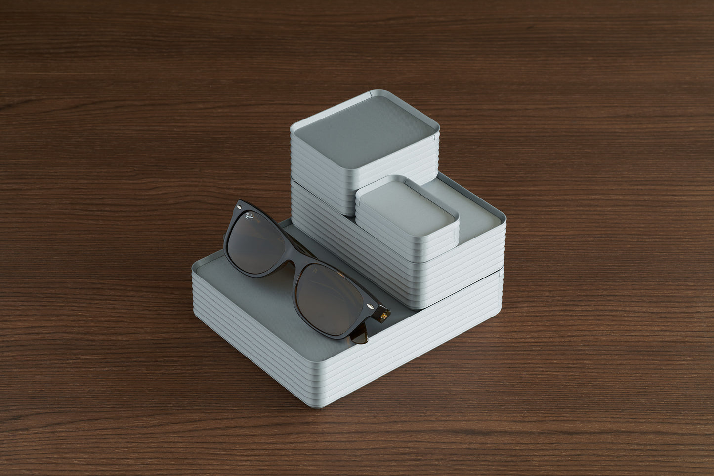 Arrangement of four silver Z Co boxes on walnut surface with sunglasses for scale
